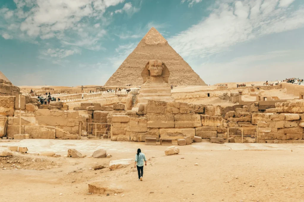 A traveler walking toward the Great Sphinx of Giza with the Pyramid of Khafre rising in the background