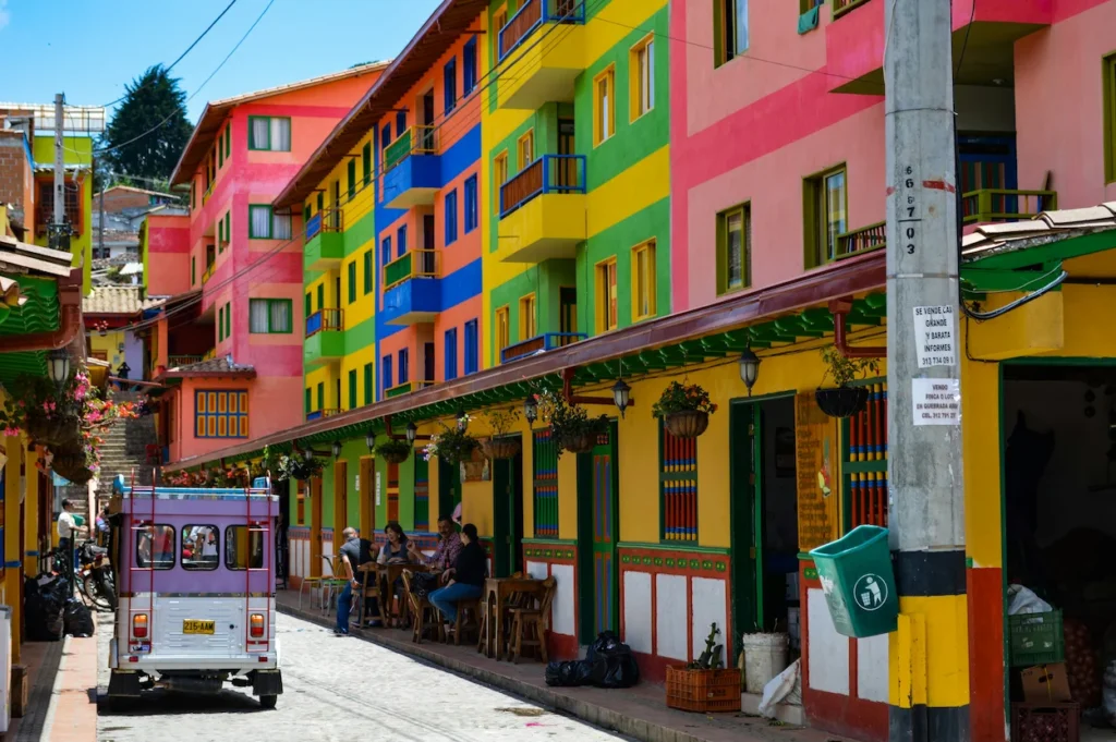 Brightly painted multi-colored buildings and a small local bus on a street in Guatapé, Colombia