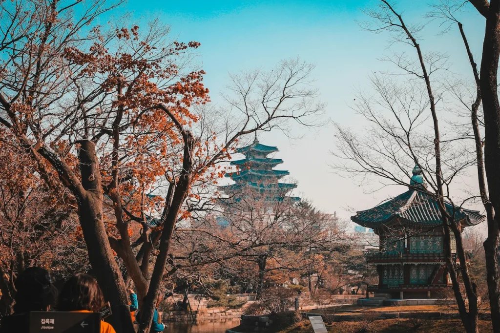 Traditional pagoda structures at Gyeongbokgung Palace framed by autumn trees in Seoul