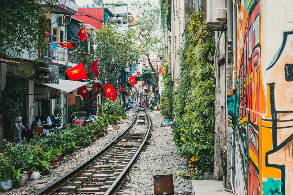 Narrow Hanoi Train Street decorated with Vietnamese flags and wall graffiti art