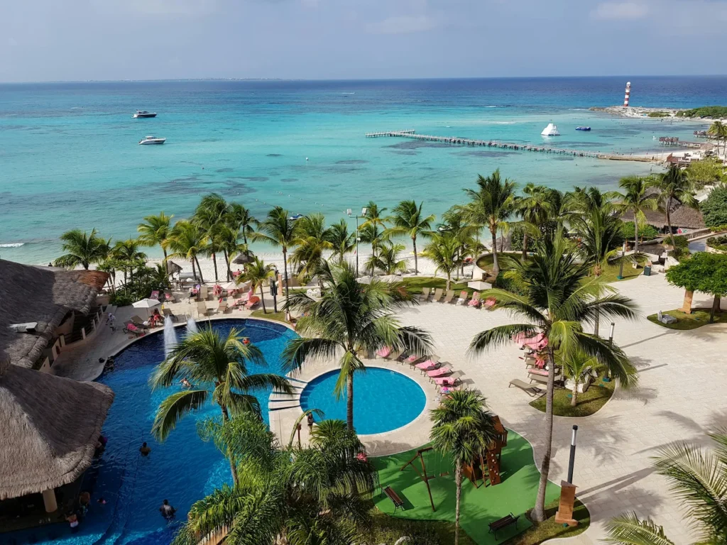 Mia Reef Isla Mujeres resort pools and palm trees overlooking boats in the turquoise Caribbean Sea