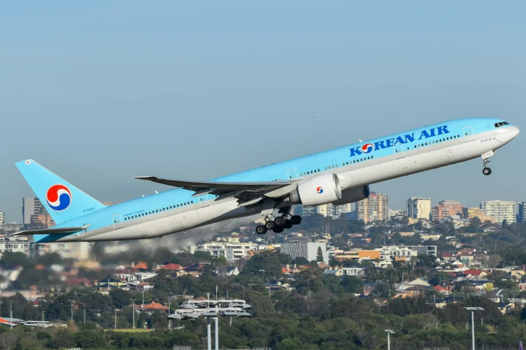 Korean Air Boeing 777-300ER commercial passenger airplane climbing into a clear blue sky during takeoff