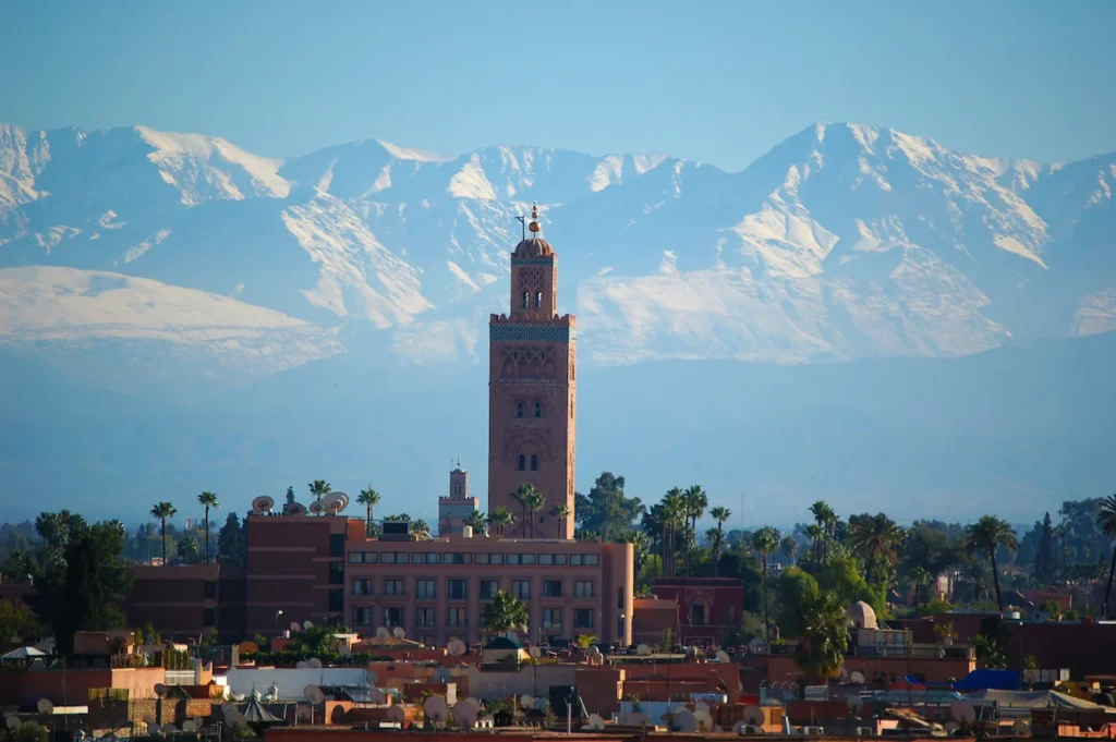 Koutoubia Mosque minaret tower in Marrakesh with the snow-covered Atlas Mountains behind it