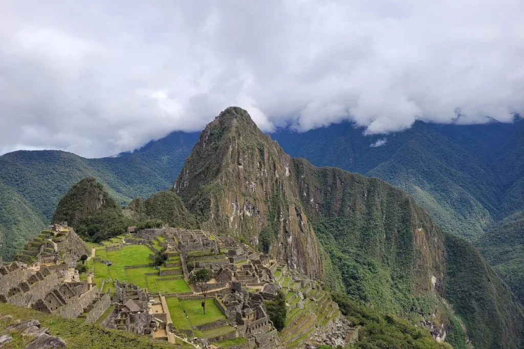 Inca citadel ruins of Machu Picchu with Huayna Picchu mountain rising behind under a cloudy sky