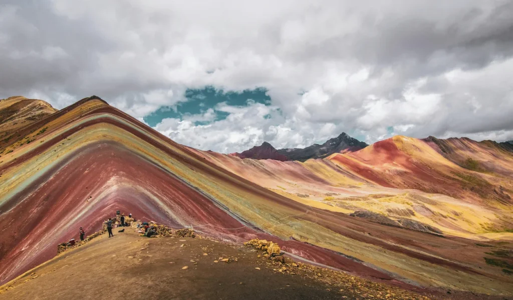 Colorful striped mineral ridges of Vinicunca Rainbow Mountain in Peru under a cloudy sky