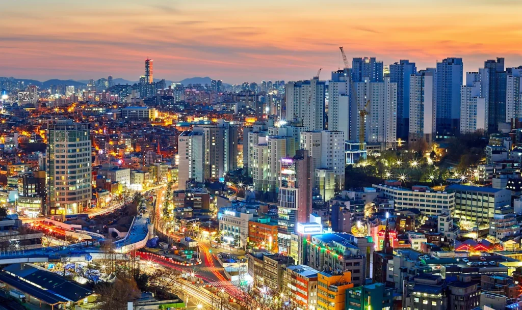 Elevated twilight view of the illuminated Seoul cityscape and high-rise apartments at sunset