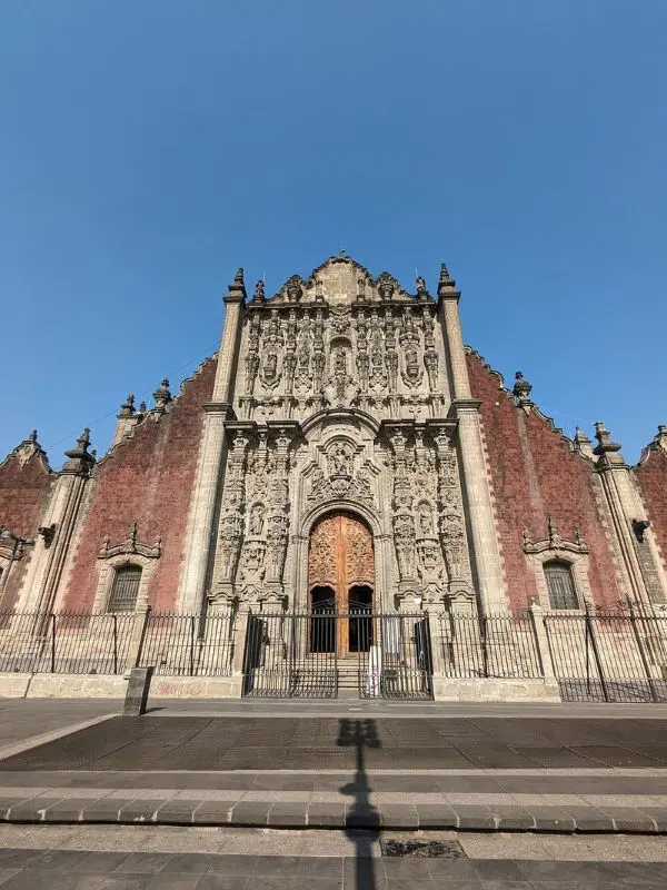 The ornate stone facade of a historic church stands in Mexico City.