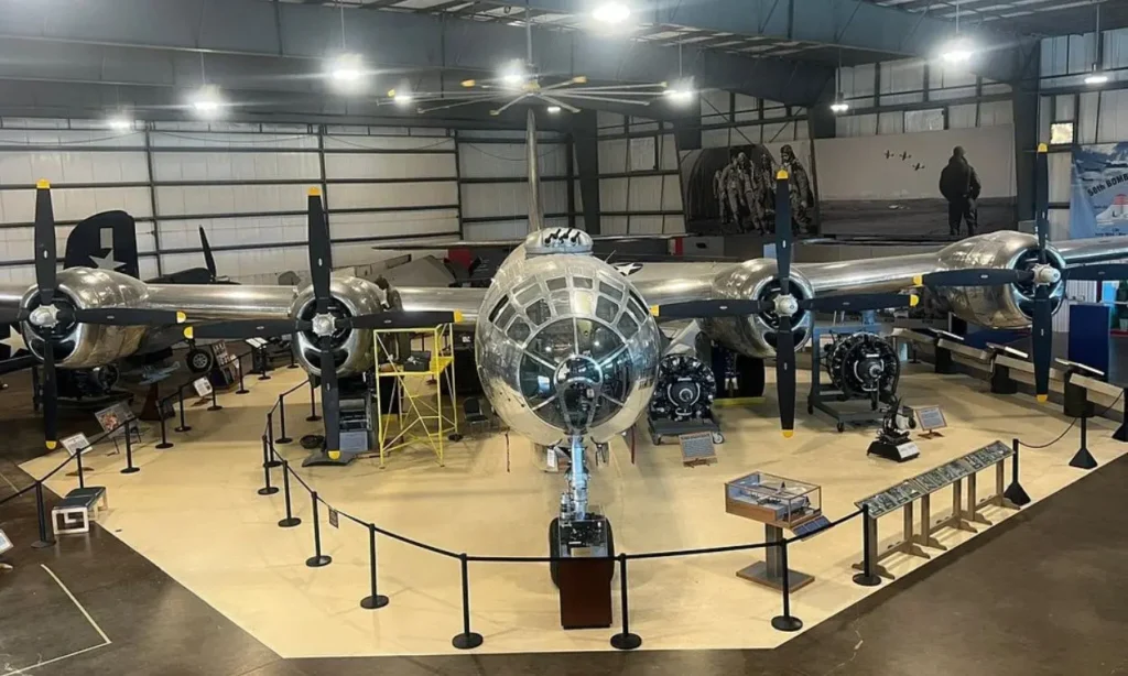 Silver bomber aircraft with four propellers on display inside The New England Air Museum.