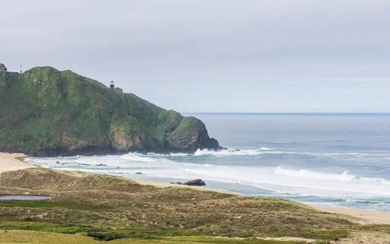Lighthouse on a green hill overlooking the ocean at Point Sur Lighthouse.