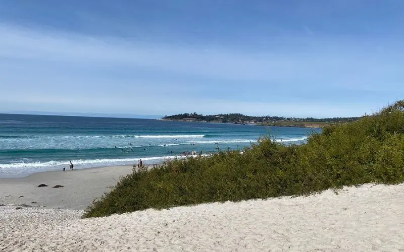 Waves rolling onto Carmel Beach with people enjoying the shoreline.