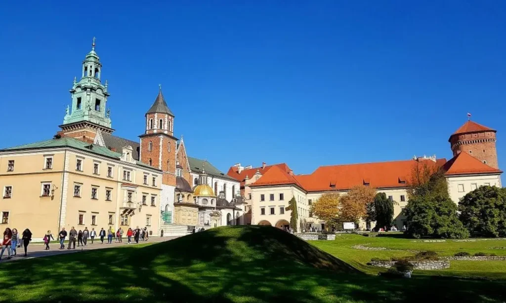 Wawel Castle stands tall with red roofs and towers against a clear blue sky.