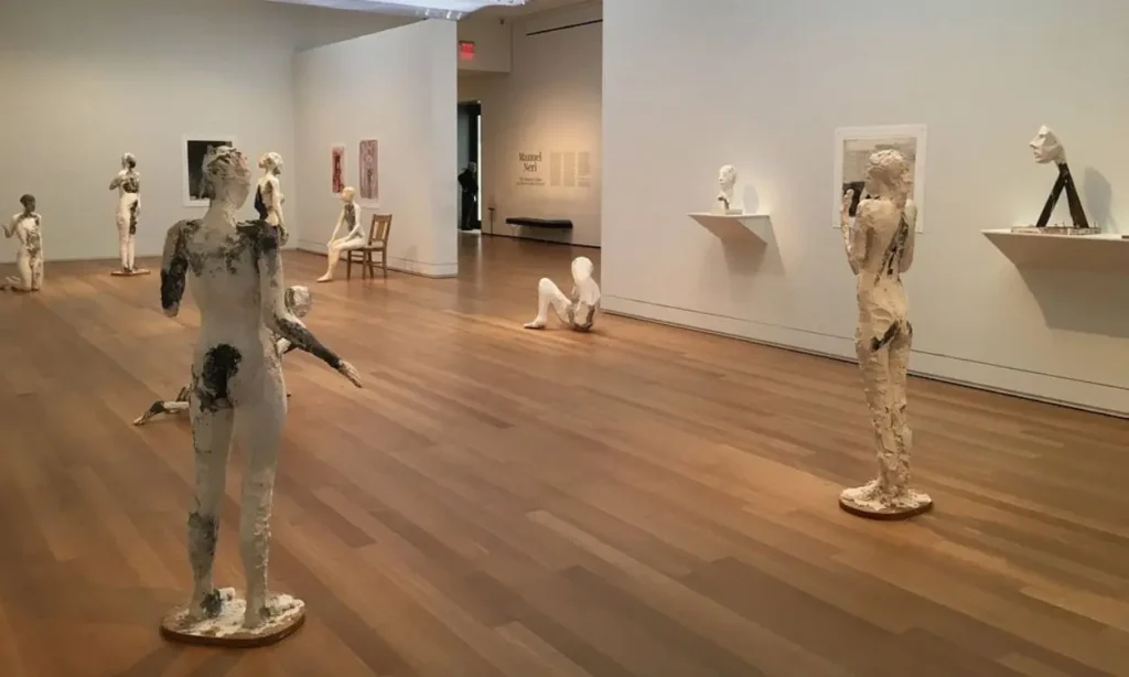 Gallery room with wooden floor displaying white textured human sculptures at Yale University Art Gallery.