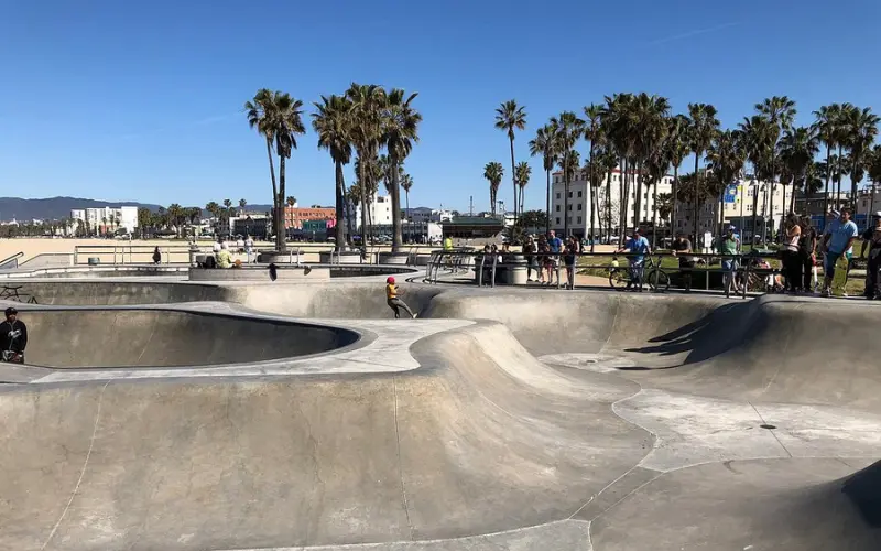Skaters riding in the concrete bowls at Venice Skatepark near the beach.