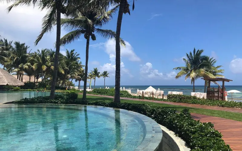Poolside with palm trees overlooking the ocean at Grand Velas Riviera Maya in Mexico.