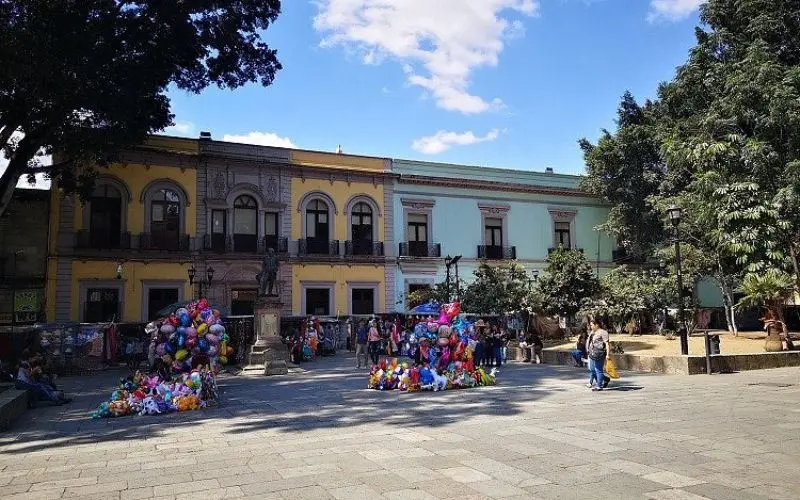 Colorful colonial buildings line a plaza in Oaxaca City.