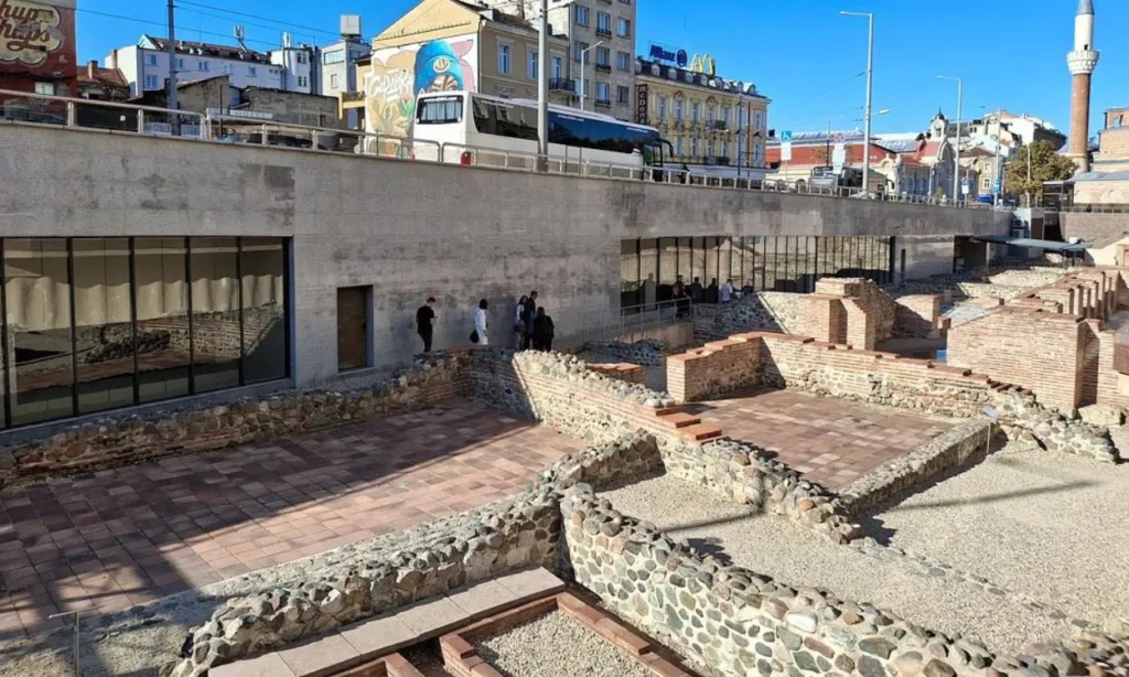 The Roman ruins of Serdica are displayed beside a modern building.