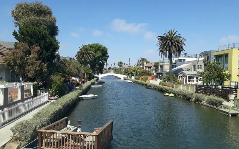 Peaceful canal with boats, palm trees, and houses at the Venice Canals.