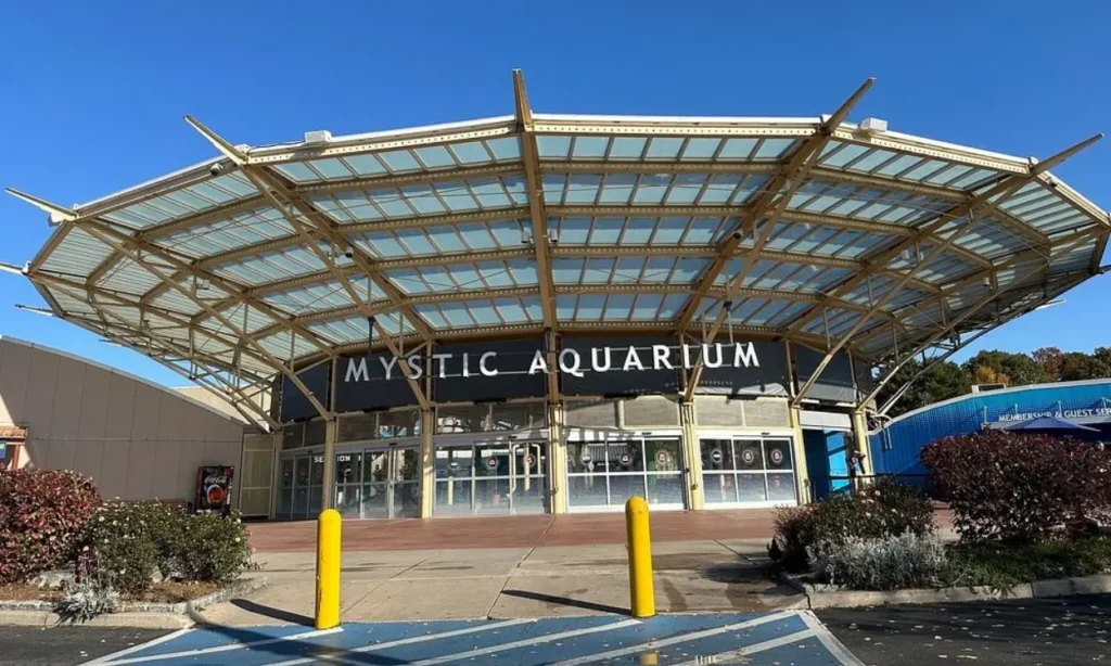 Entrance with a large glass canopy and signage at Mystic Aquarium.