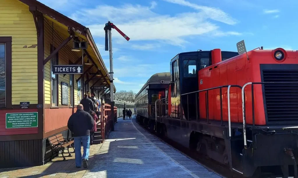 People boarding a vintage red and black train at the Essex Steam Train & Riverboat station.