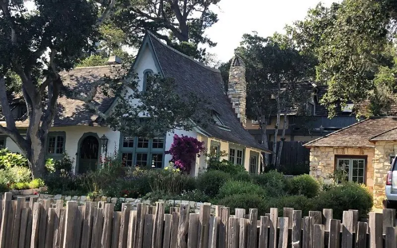 A storybook-style home surrounded by trees and flowers in Carmel's Fairytale Cottages.