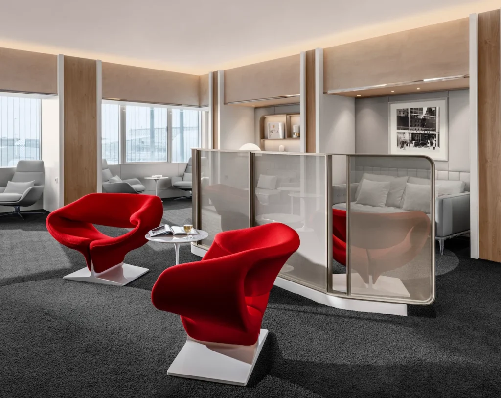 Air France La Premiere Lounge seating area with red wave chairs, grey carpets, and metallic privacy screens