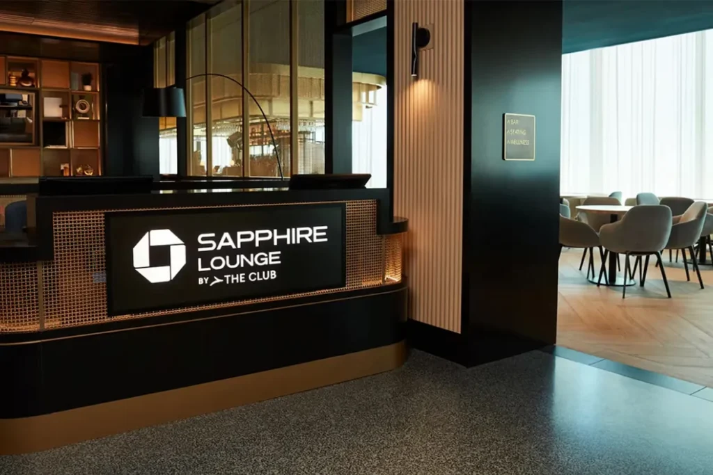 Front check-in reception desk displaying the Chase Sapphire Lounge by The Club logo sign