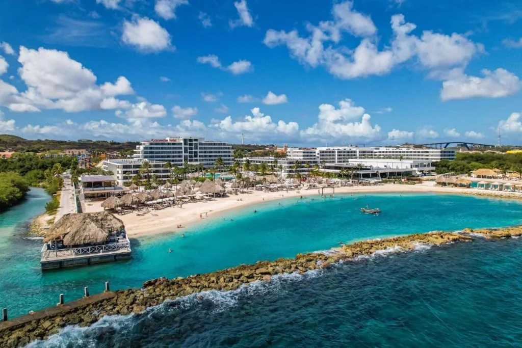 Aerial view of Corendon Mangrove Beach Resort with white sand, turquoise water, and a stone breakwater