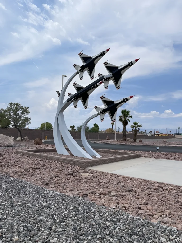 Outdoor monument of four Thunderbird fighter jet replicas in a diamond formation mounted on curved white pillars