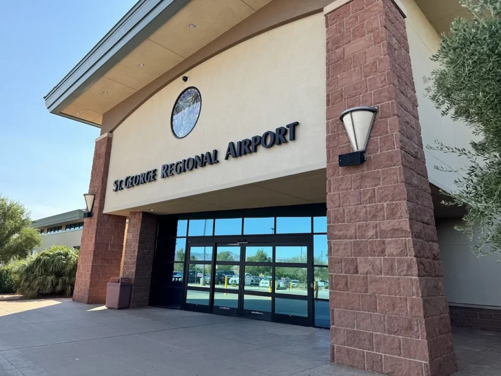 Exterior entrance of the St George Regional Airport terminal building with prominent red brick pillars and glass doors