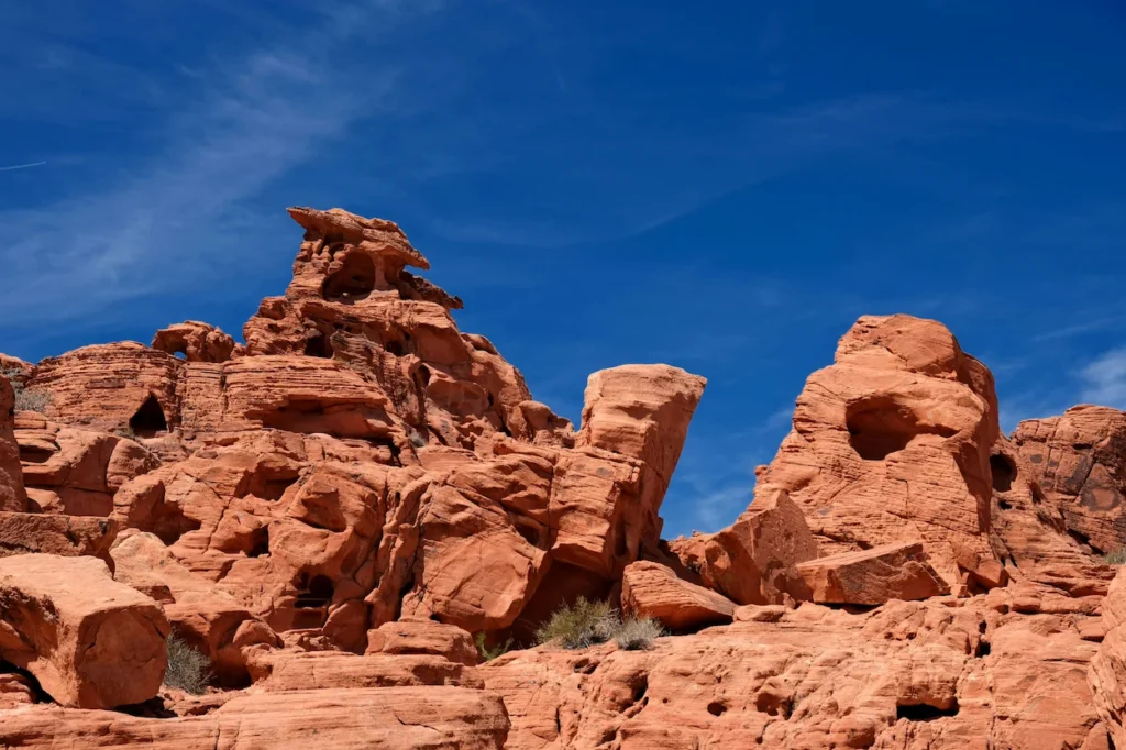 Vibrant red sandstone rock formations with natural holes and eroded crevices against a blue sky