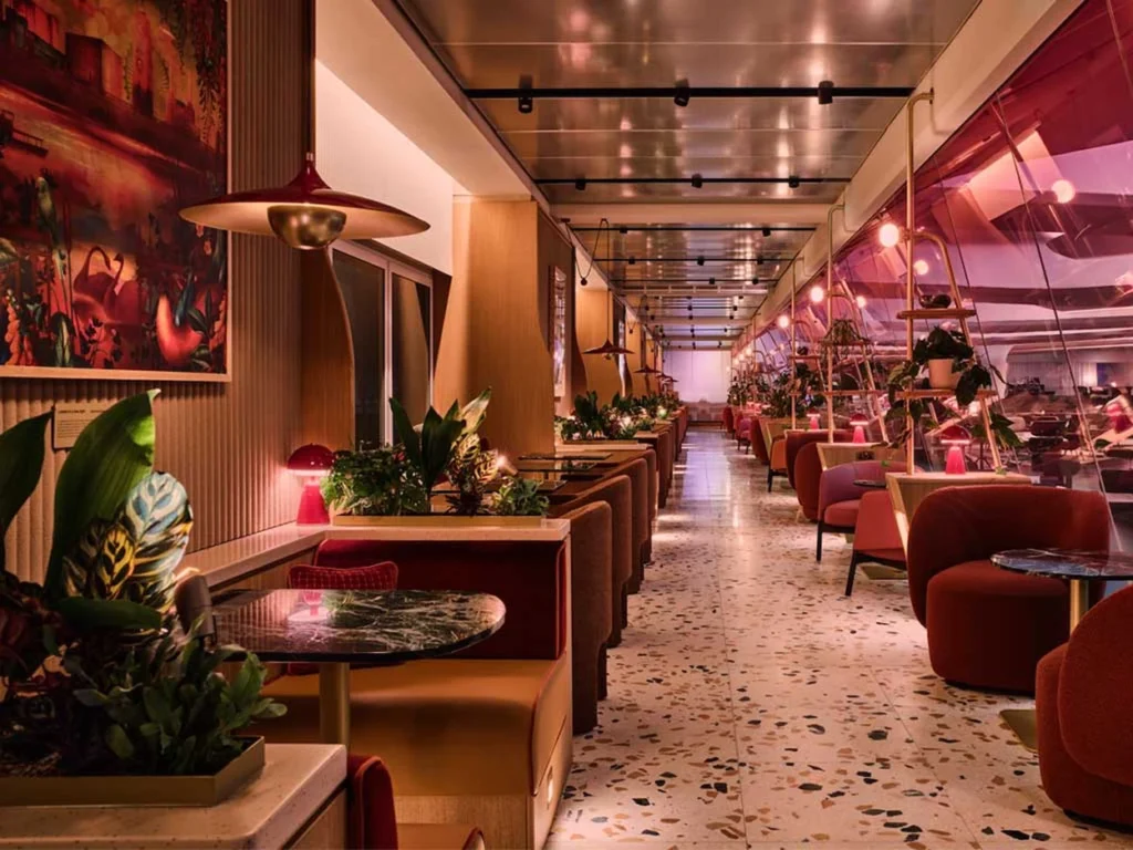 Virgin Atlantic Clubhouse seating area with red retro armchairs, terrazzo floors, and pink tinted windows
