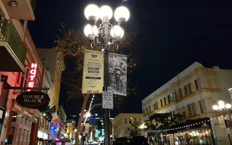 Streetlights glow over the lively Gaslamp Quarter at night.