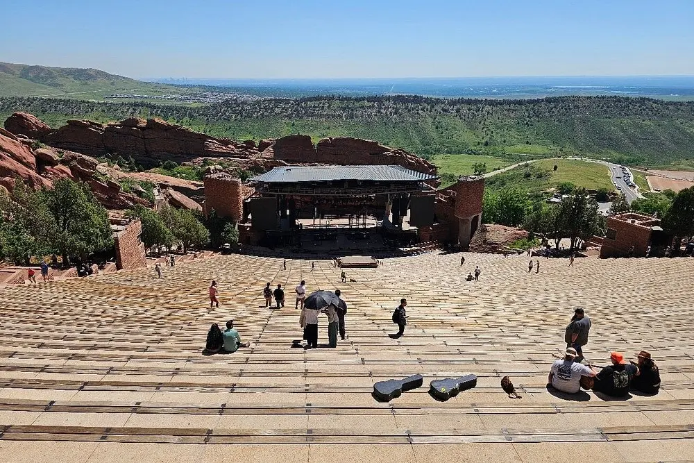 People walking the wide steps of the Red Rocks Amphitheatre with the stage below.