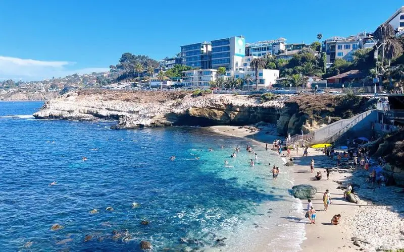 Swimmers and sunbathers at the rocky shoreline of La Jolla Cove.