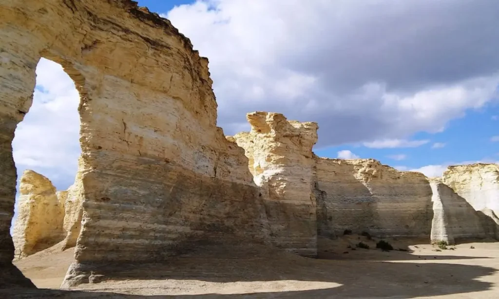 Tall chalk formations at Monument Rocks under a partly cloudy sky.
