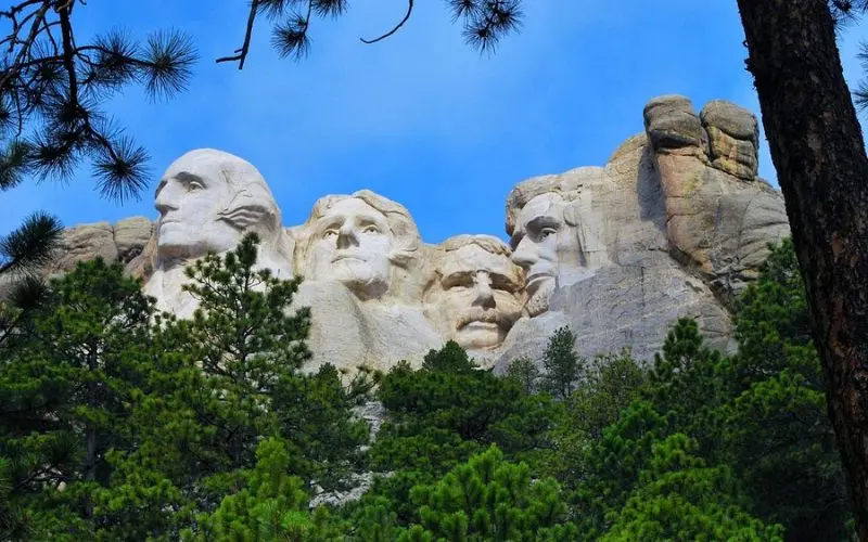 The carved presidential faces at Mount Rushmore National Memorial rise above the trees.