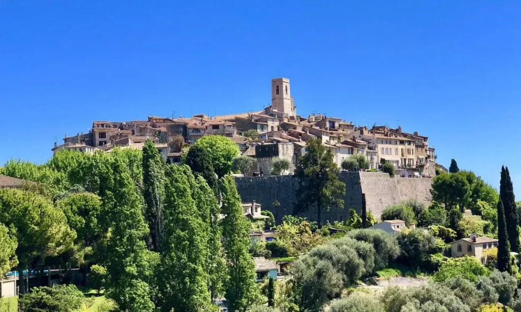 A scenic view of Saint-Paul de Vence village perched on a hill surrounded by greenery.