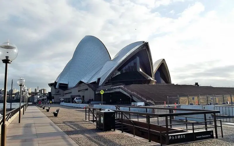 View of the Sydney Opera House with its iconic sail-like roof from the waterfront walkway.
