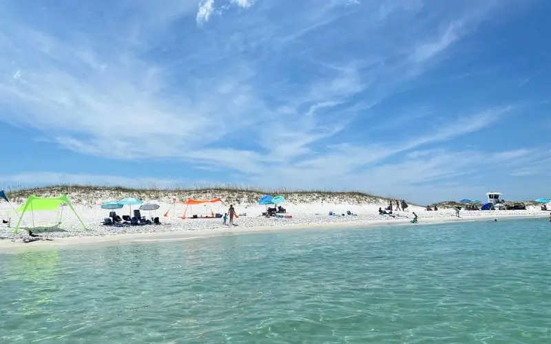 Colorful tents and beachgoers relaxing at Crab Island Adventure.