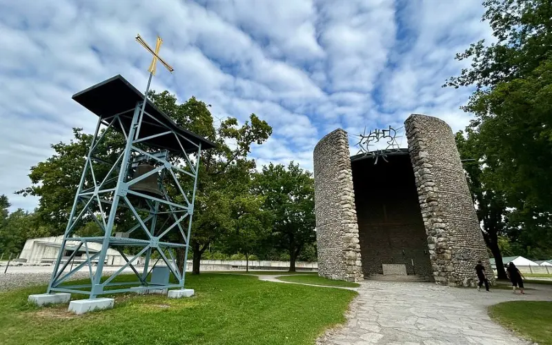 Stone chapel and metal tower at Dachau Memorial site.