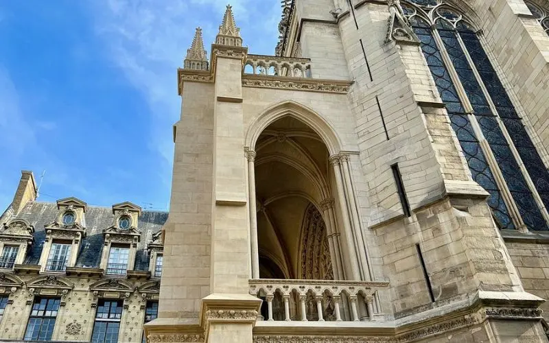 Exterior view of Sainte-Chapelle with Gothic arches and stone carvings in central Paris.