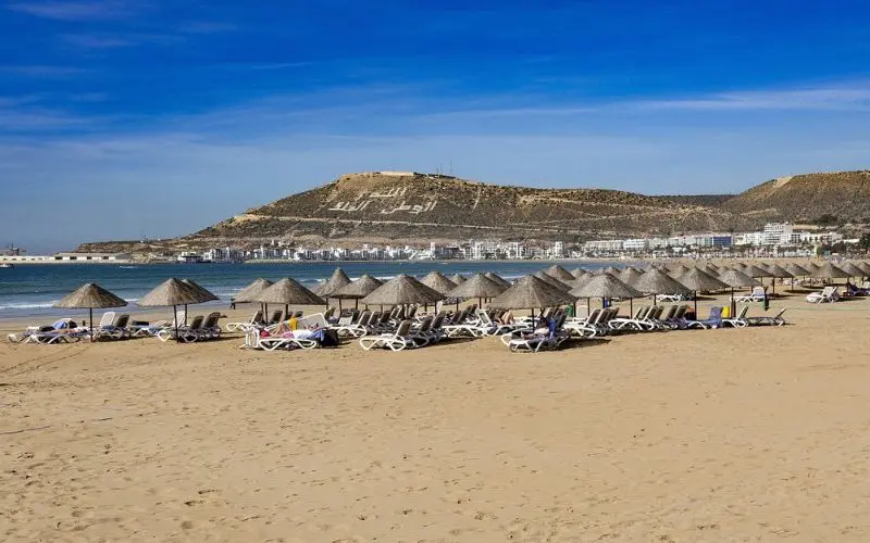 Sandy beach with umbrellas and lounge chairs in Agadir.
