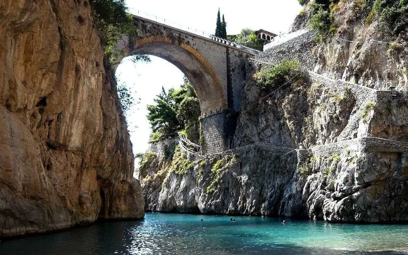 Stone bridge over turquoise water at Furore Fjord.