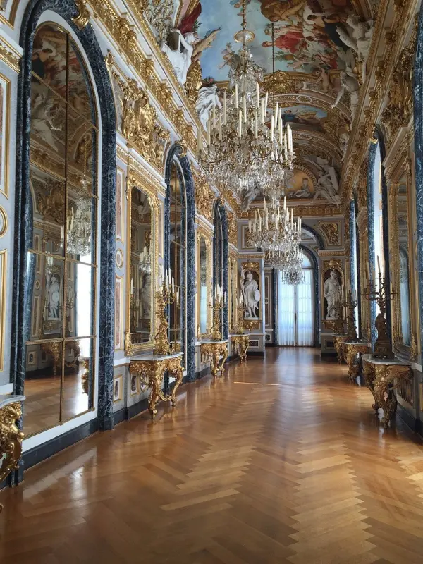 Ornate hallway with chandeliers and gold decor in Herrenchiemsee Palace.