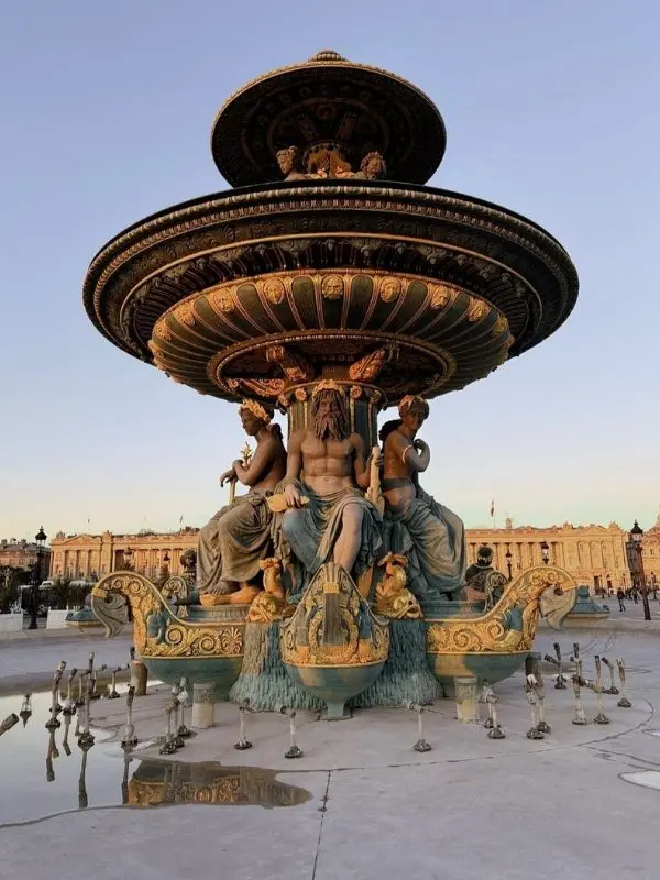 Fountain at Place de la Concorde in Paris with ornate sculptures of figures and sea creatures.