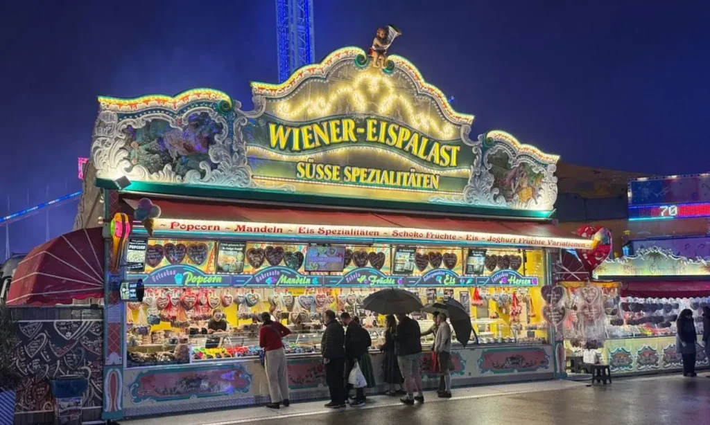 Colorful Wiener-Eispalast sweets stand at Oktoberfest in Munich during the evening.