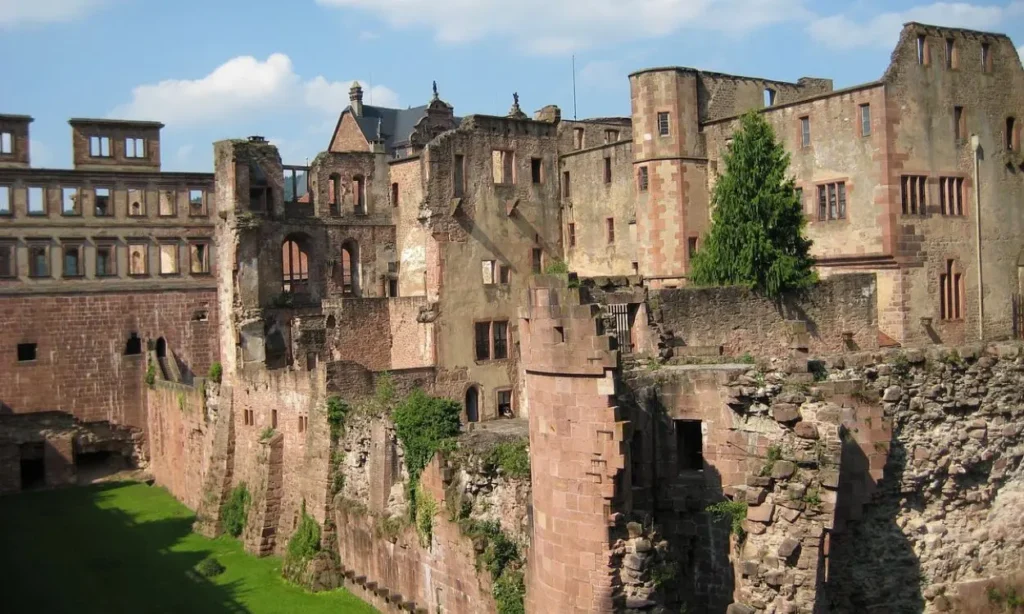 The ruins of Heidelberg Castle with red stone walls and towers.