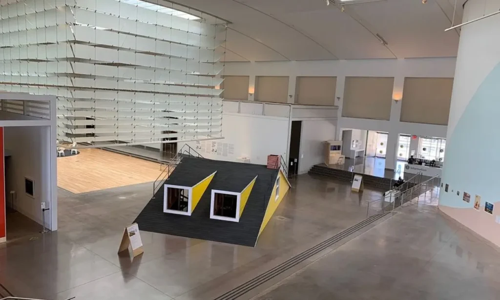 A view inside Queens Museum shows modern exhibits and open gallery space.