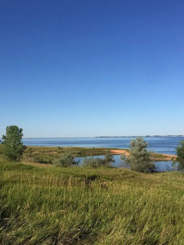 Calm blue water and grassy shoreline at Lake Sakakawea.