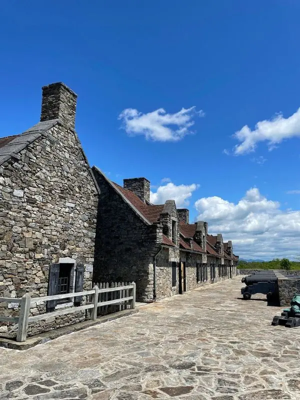 The stone buildings of Fort Ticonderoga stand under a bright blue sky.